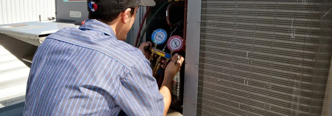 HVAC technician servicing a condenser unit in Stafford